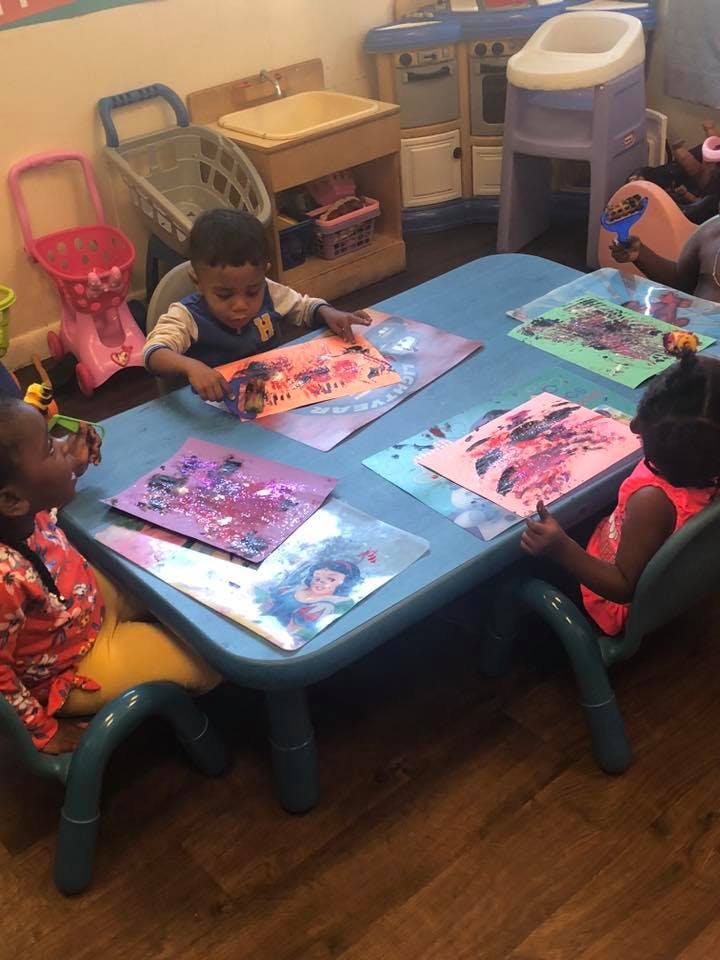 Children painting at a table in a classroom