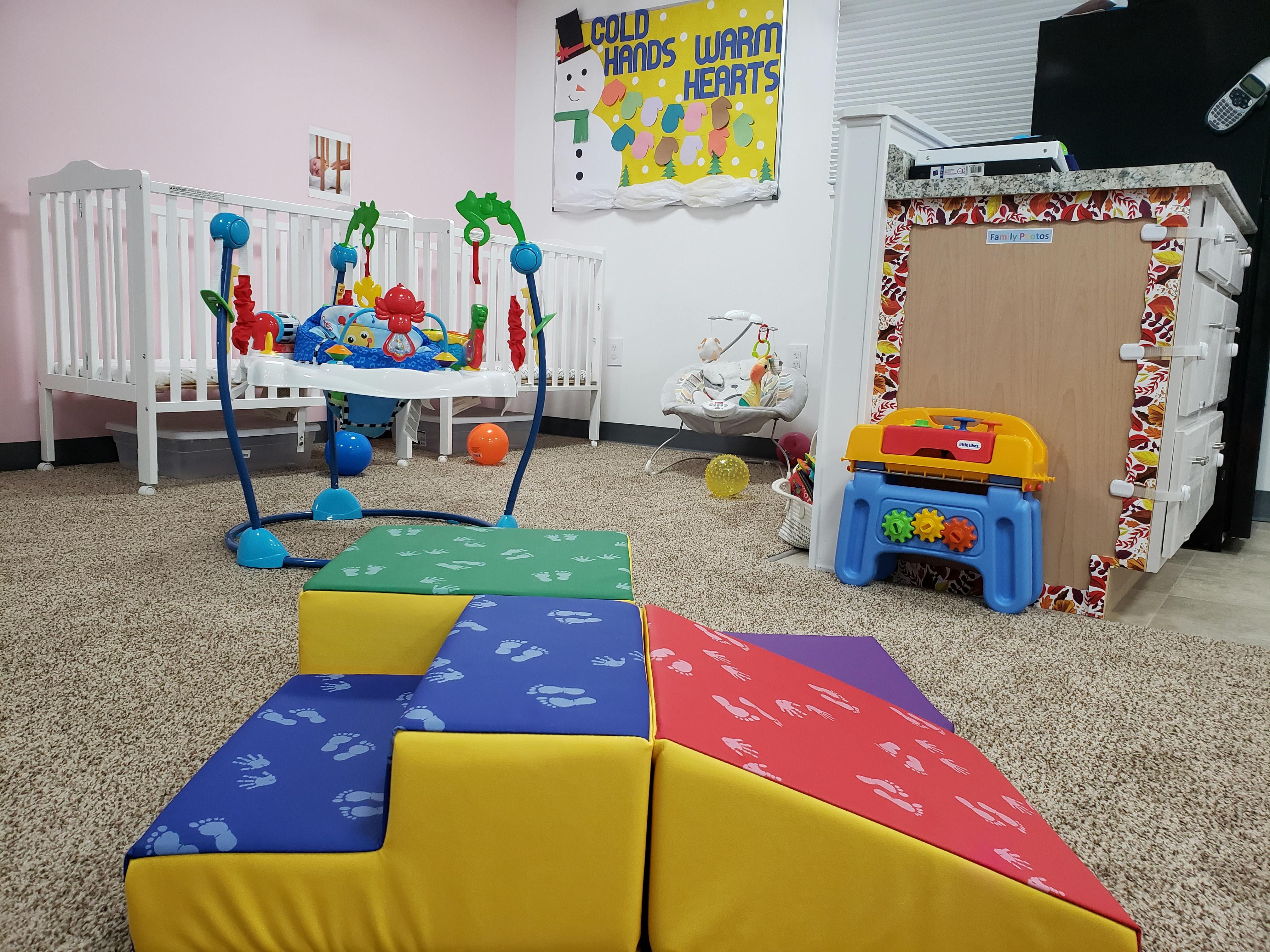 Baby play area with soft play equipment, bouncer, and cribs