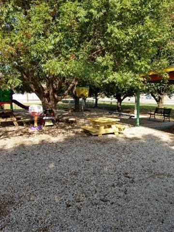 Playground with trees, a yellow picnic table, and play equipment