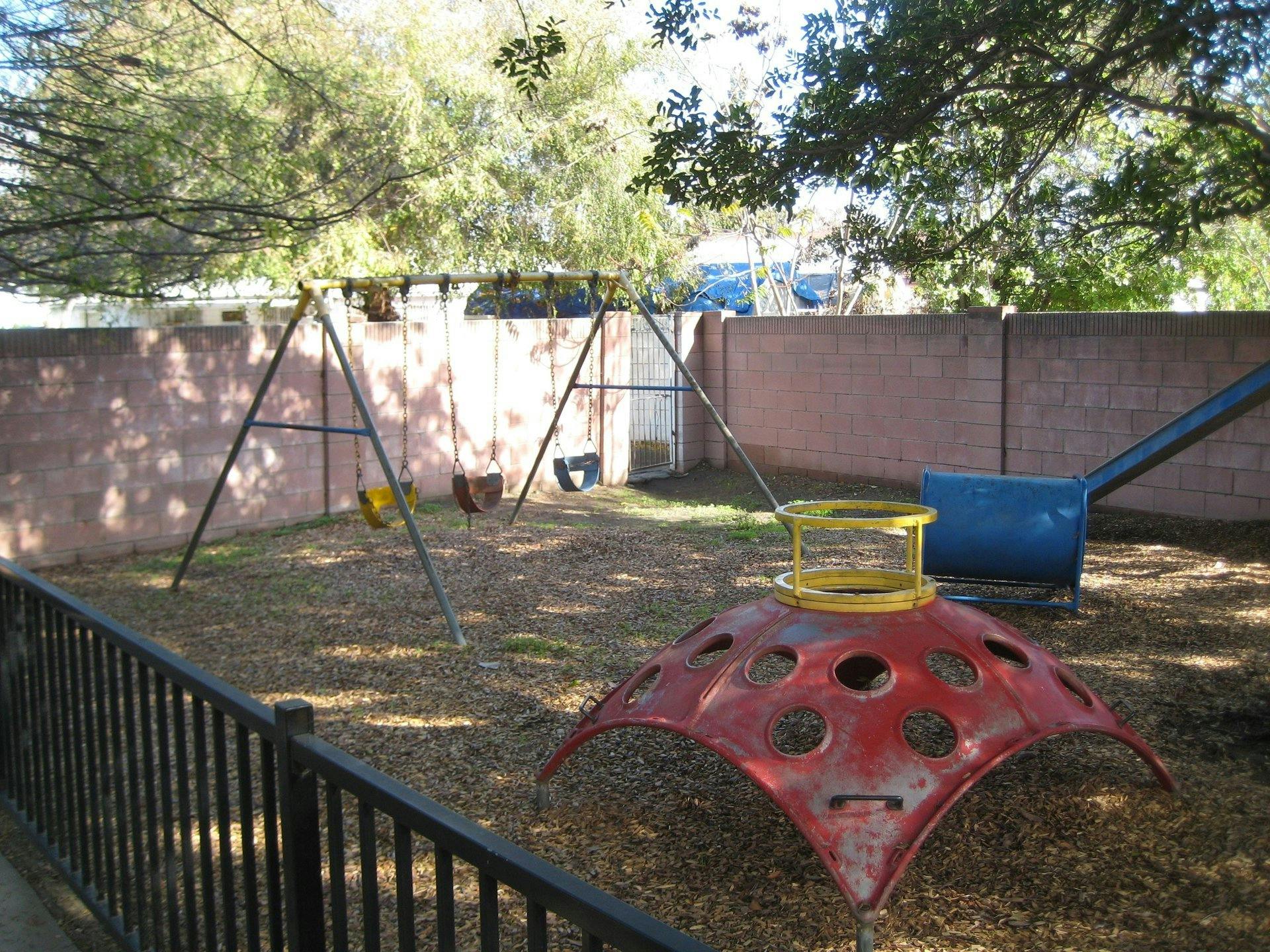 Playground with swings, a red climbing dome, and a blue slide