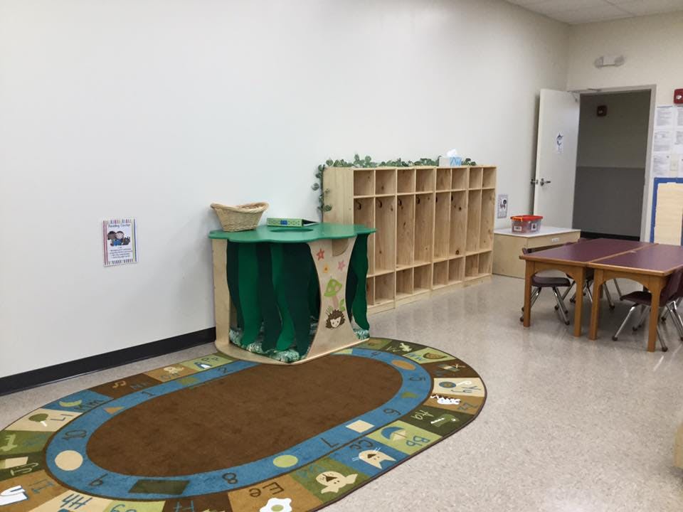 Empty classroom with rug, cubbies, and small tables