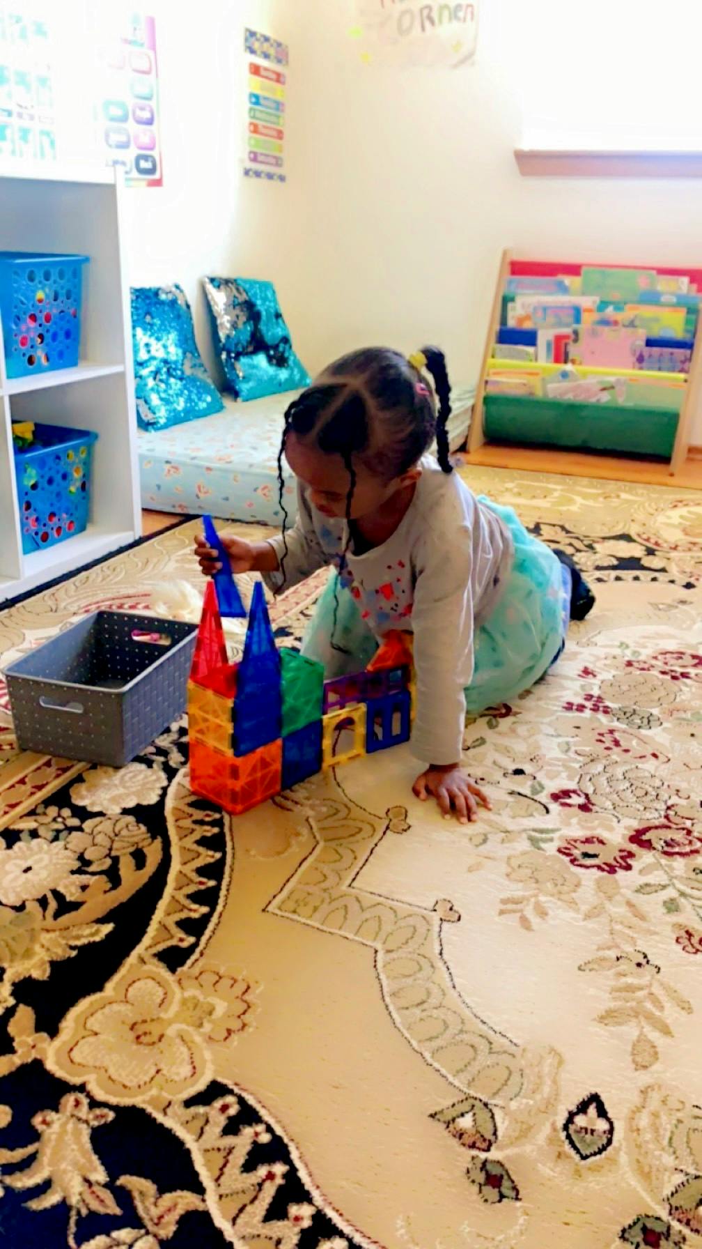 Child playing with colorful magnetic building blocks on a rug