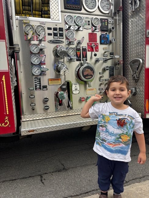 Child standing in front of a fire truck control panel
