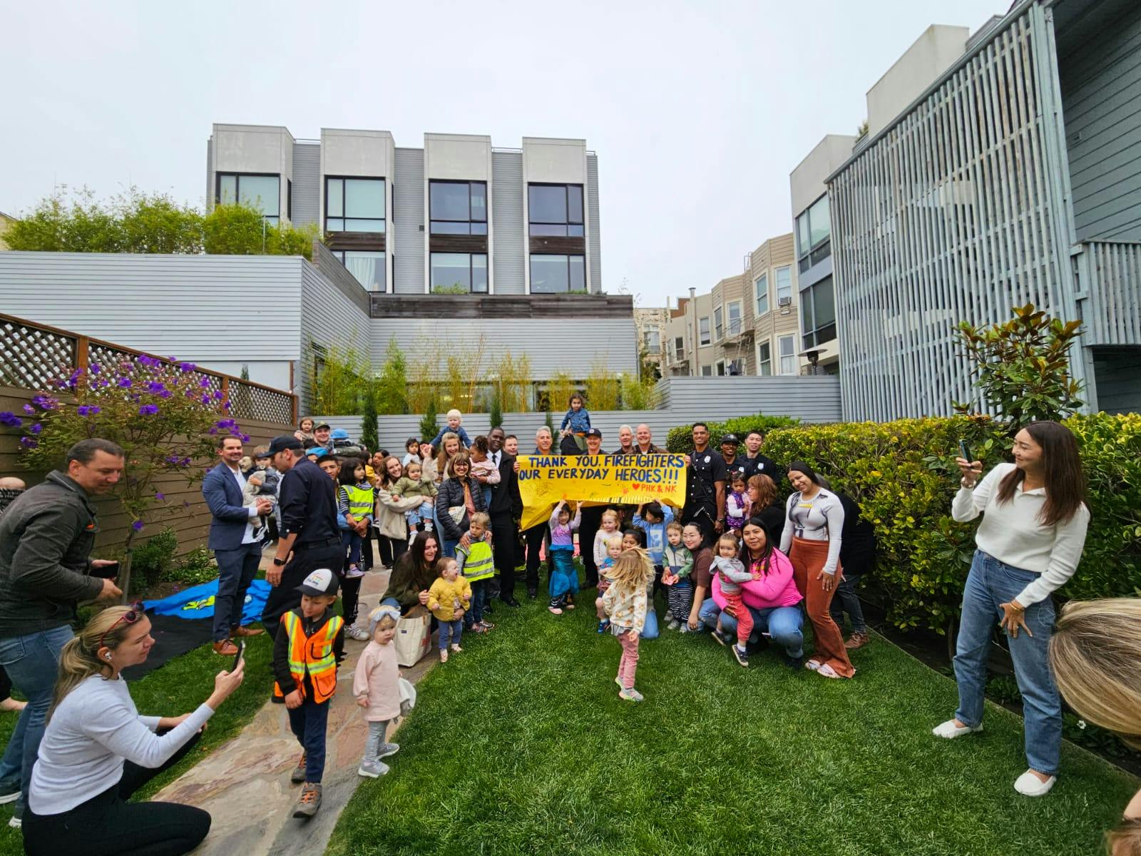 Group of people and children holding a yellow banner on a lawn