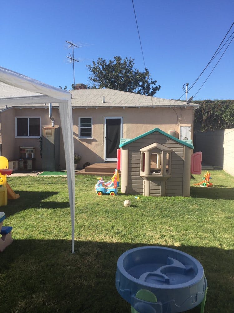 Backyard with a playhouse, toys, and a small house in-ground pool