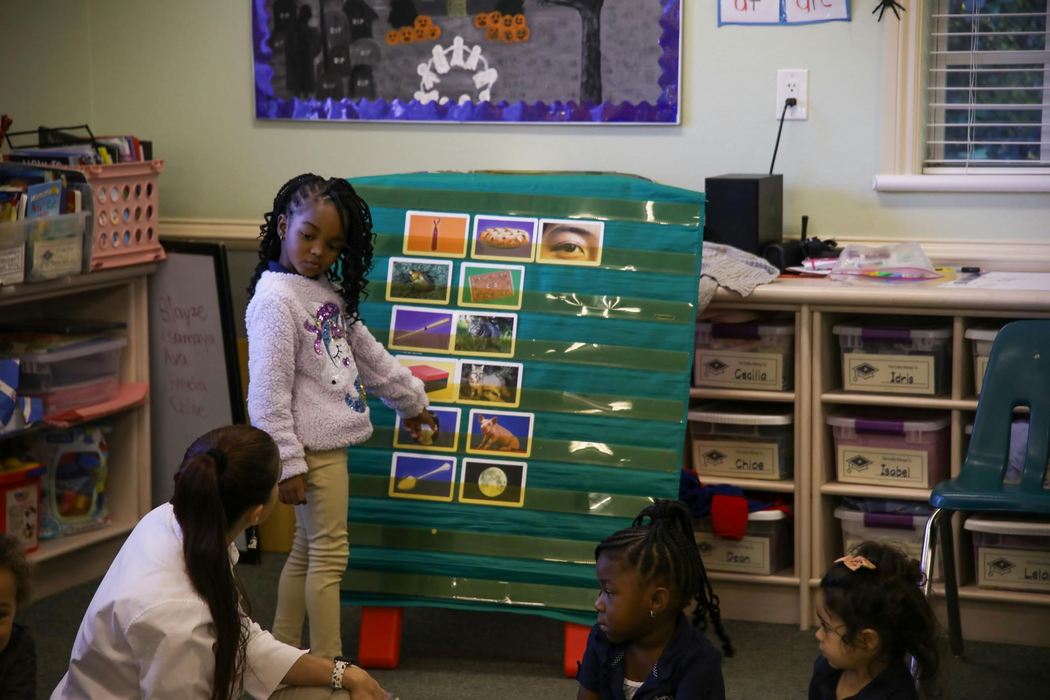Child pointing at pictures on a display board in a classroom