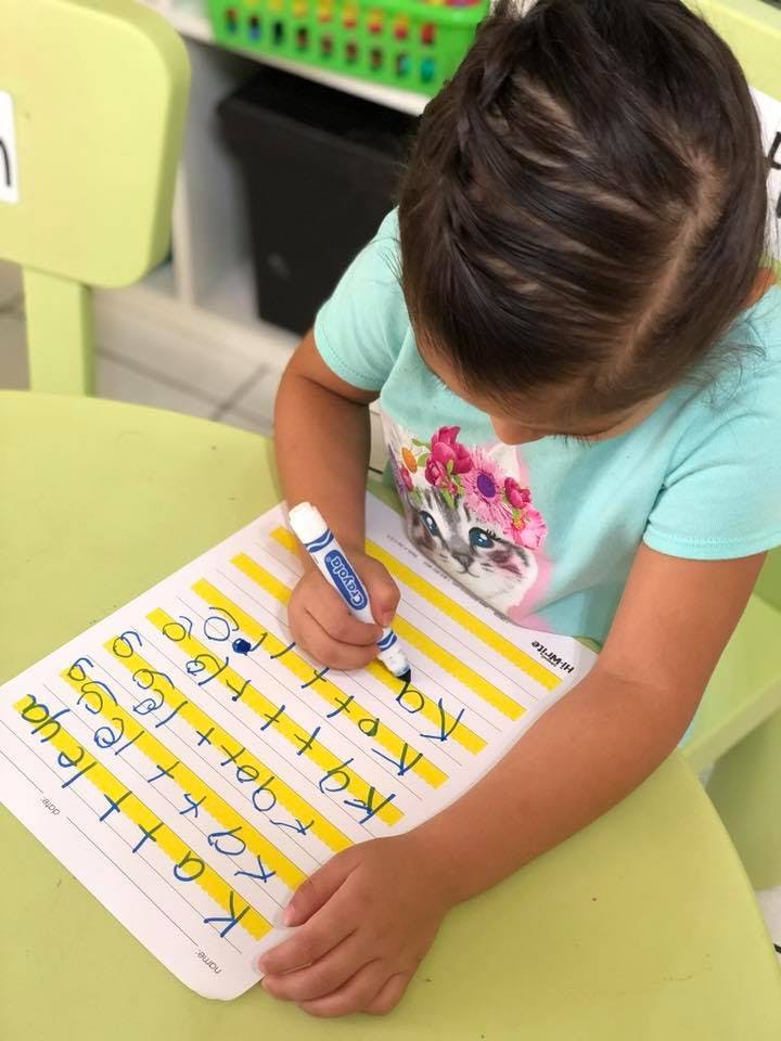 Child writing on a worksheet with a marker