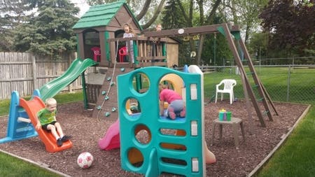 Children playing on a backyard playset with slides and swings