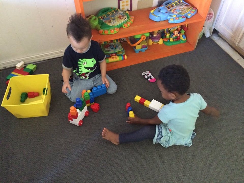 Two children playing with building blocks on the floor