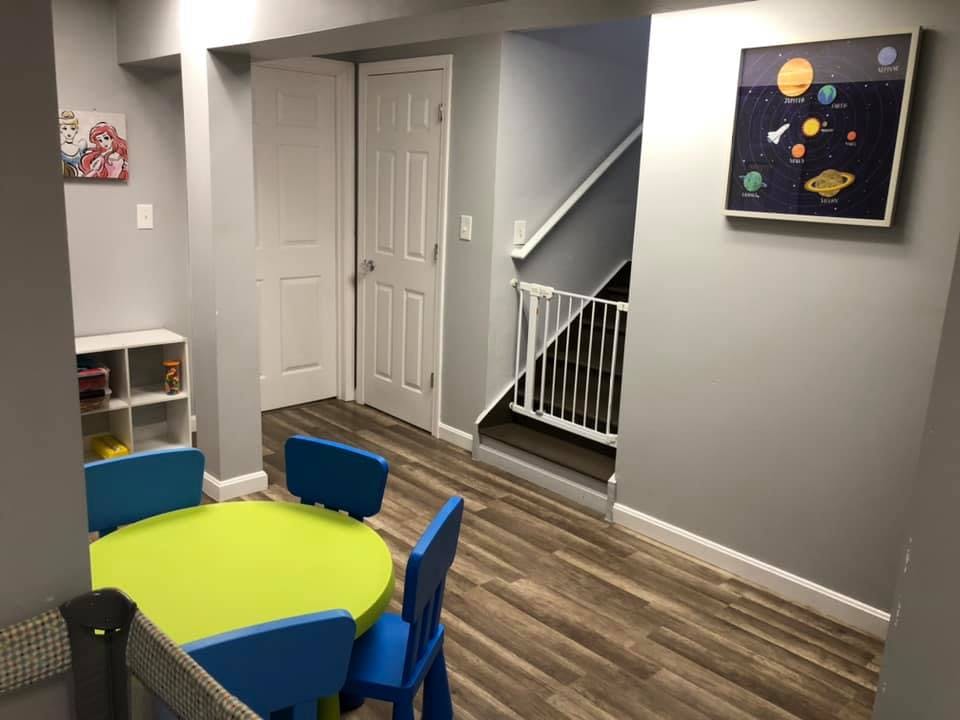 Playroom with a green table and blue chairs, stairs with a baby gate