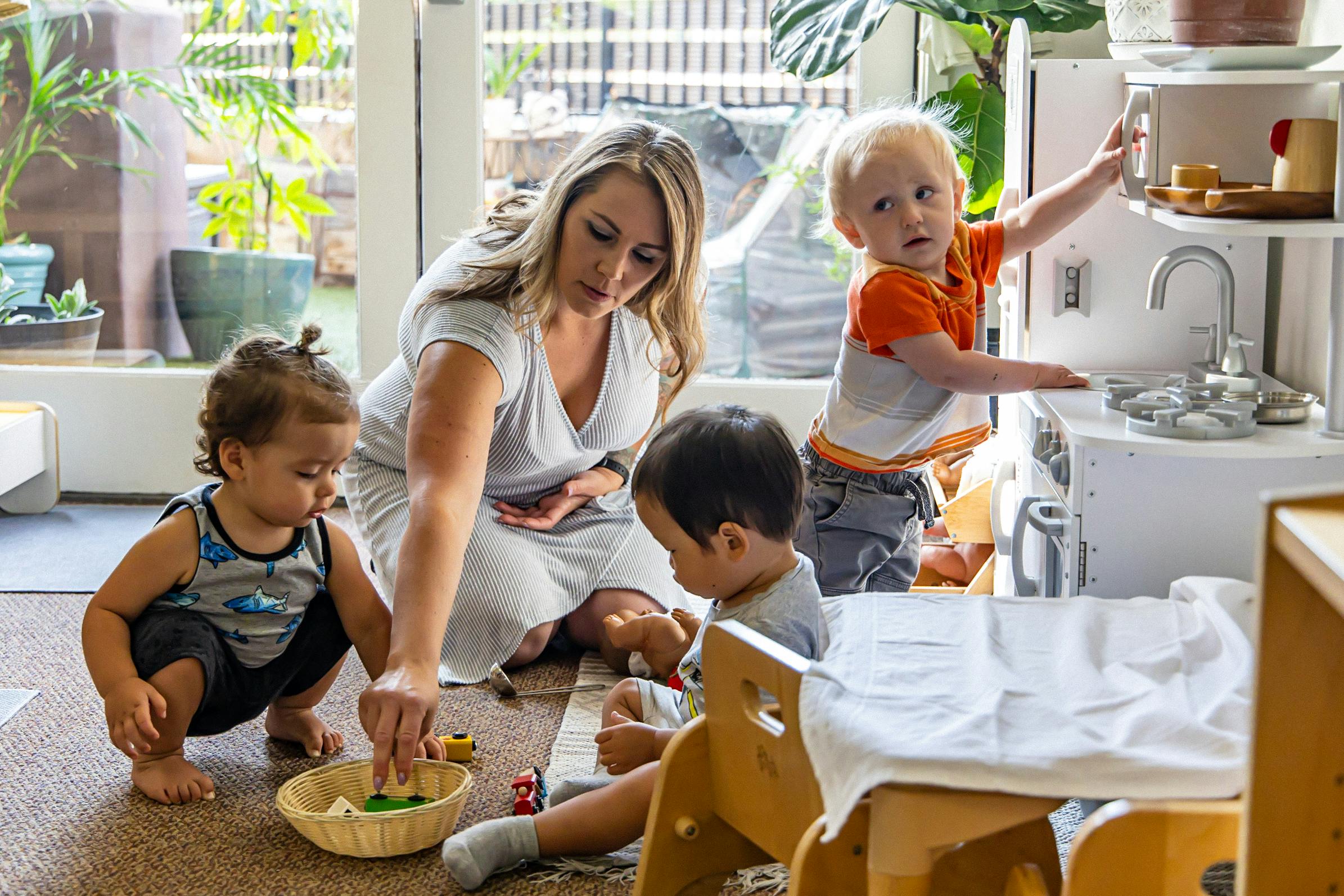 Adult and three children playing with toys in a classroom