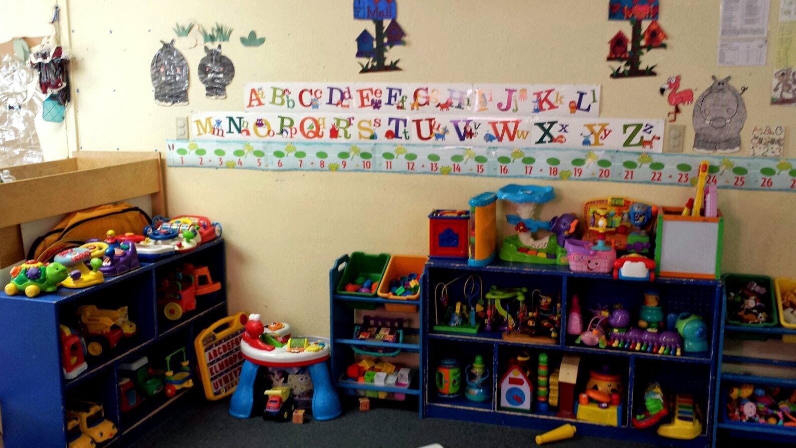 Classroom with shelves of toys and alphabet chart on wall