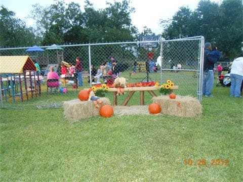 Outdoor fall display with pumpkins, hay bales, and sunflowers