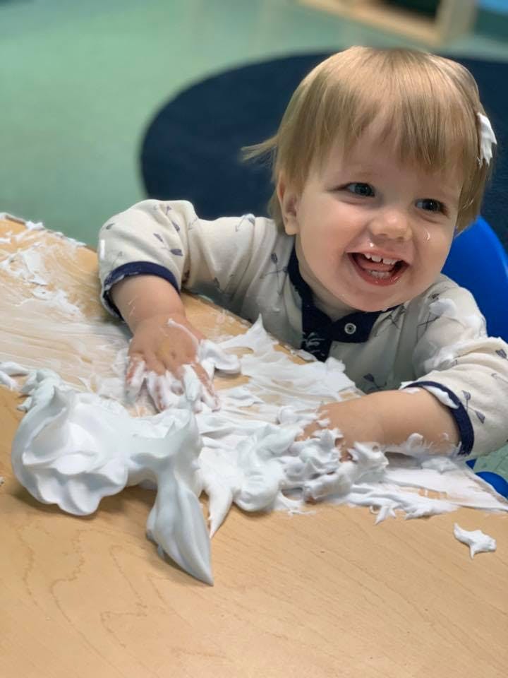Child playing with shaving cream on a table