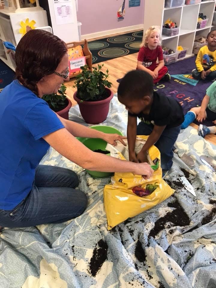 Adult and child planting in a classroom