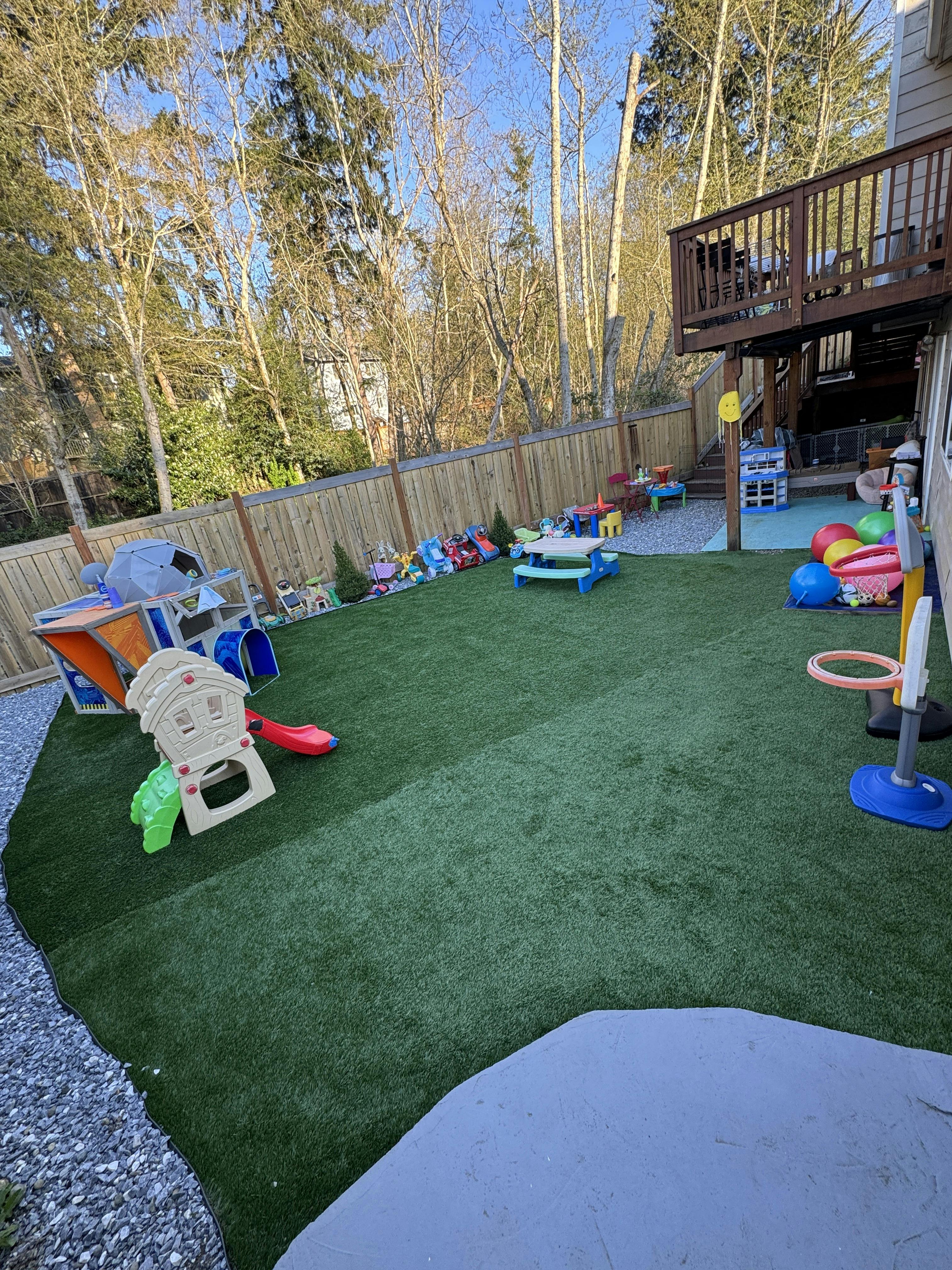 Backyard with artificial turf, children's play structures, and toys