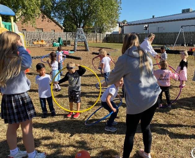 Adults and children playing with hula hoops on a playground