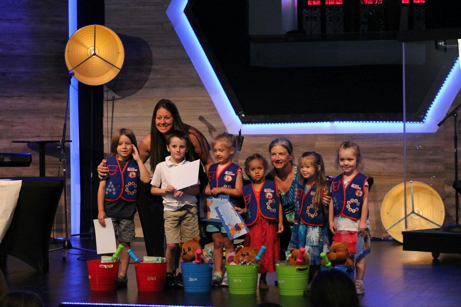Adults and children on a stage with buckets