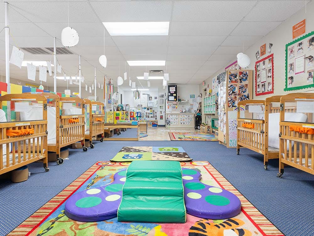 Cribs and play mats in a bright daycare classroom