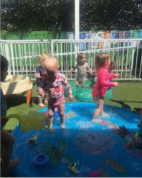 Group of children playing with water in a small pool outdoors