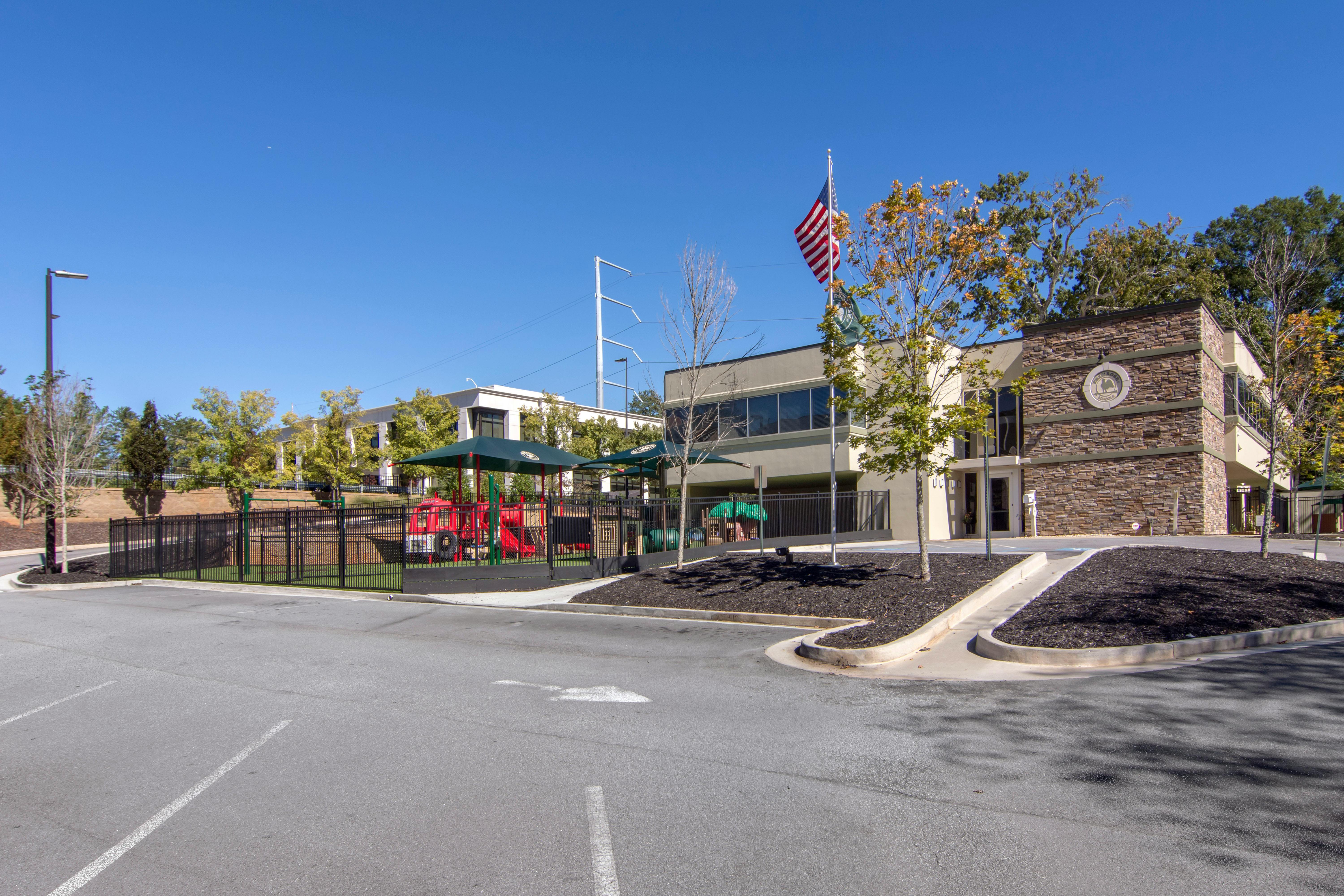 A school building with a fenced playground and an American flag flying