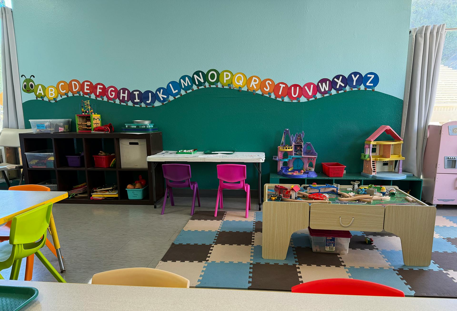 Classroom interior with an alphabet caterpillar on the wall and play equipment
