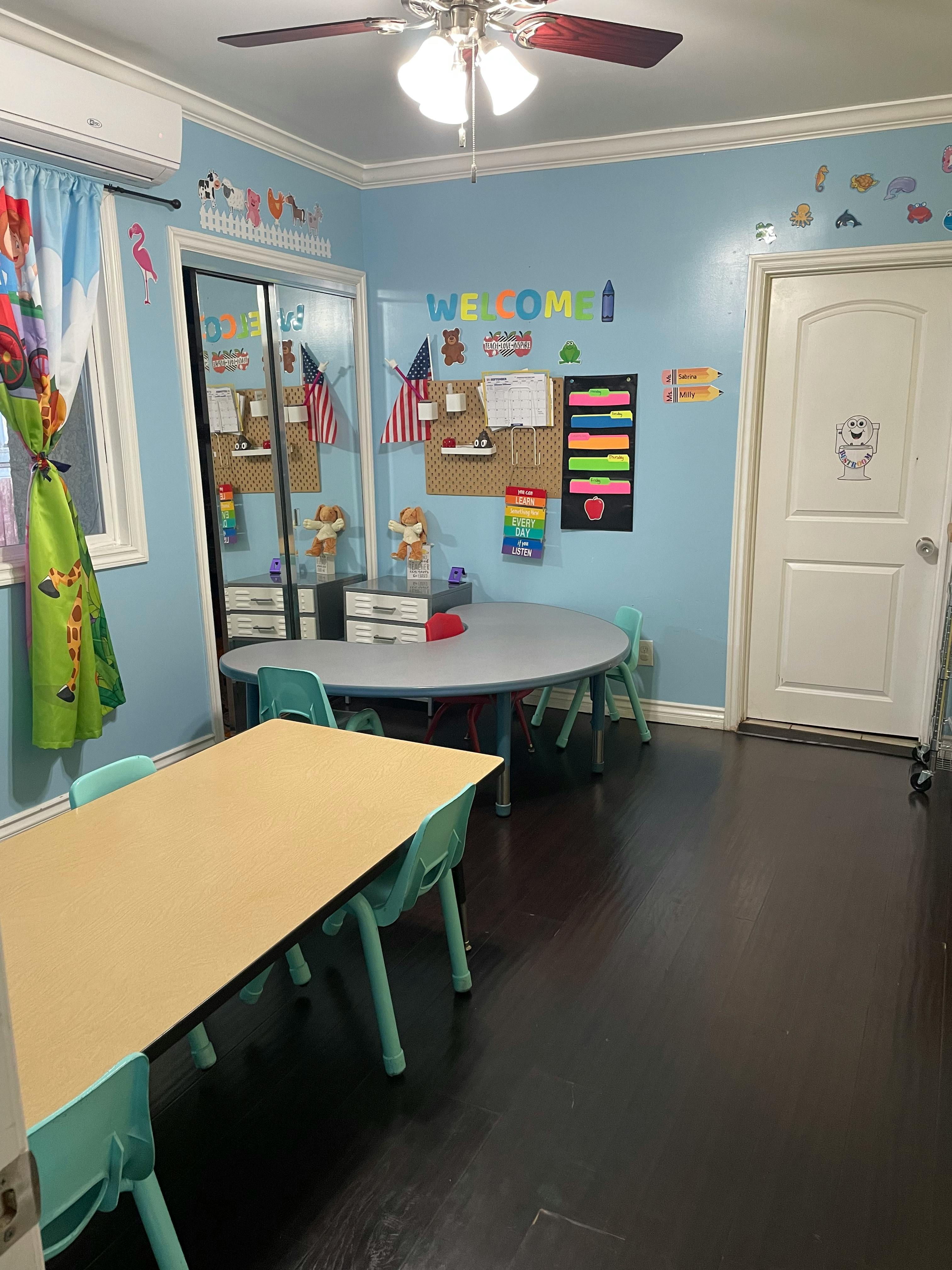 Classroom with tables and chairs, bulletin board, and ceiling fan
