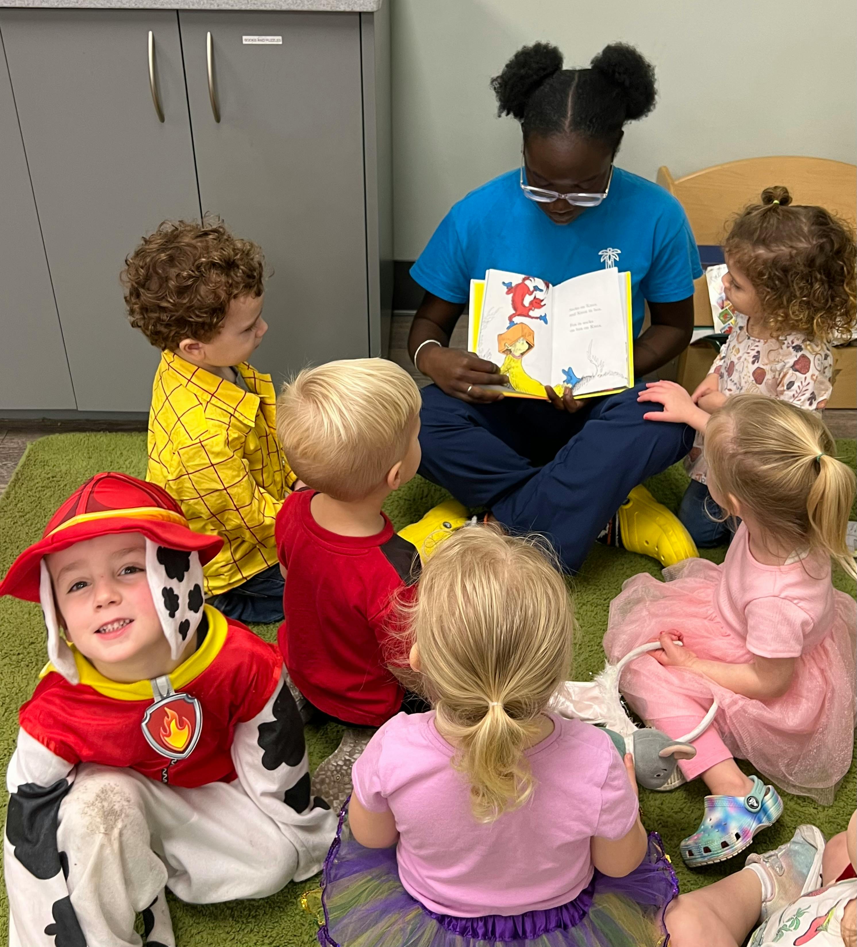 Person reading a book to a group of children