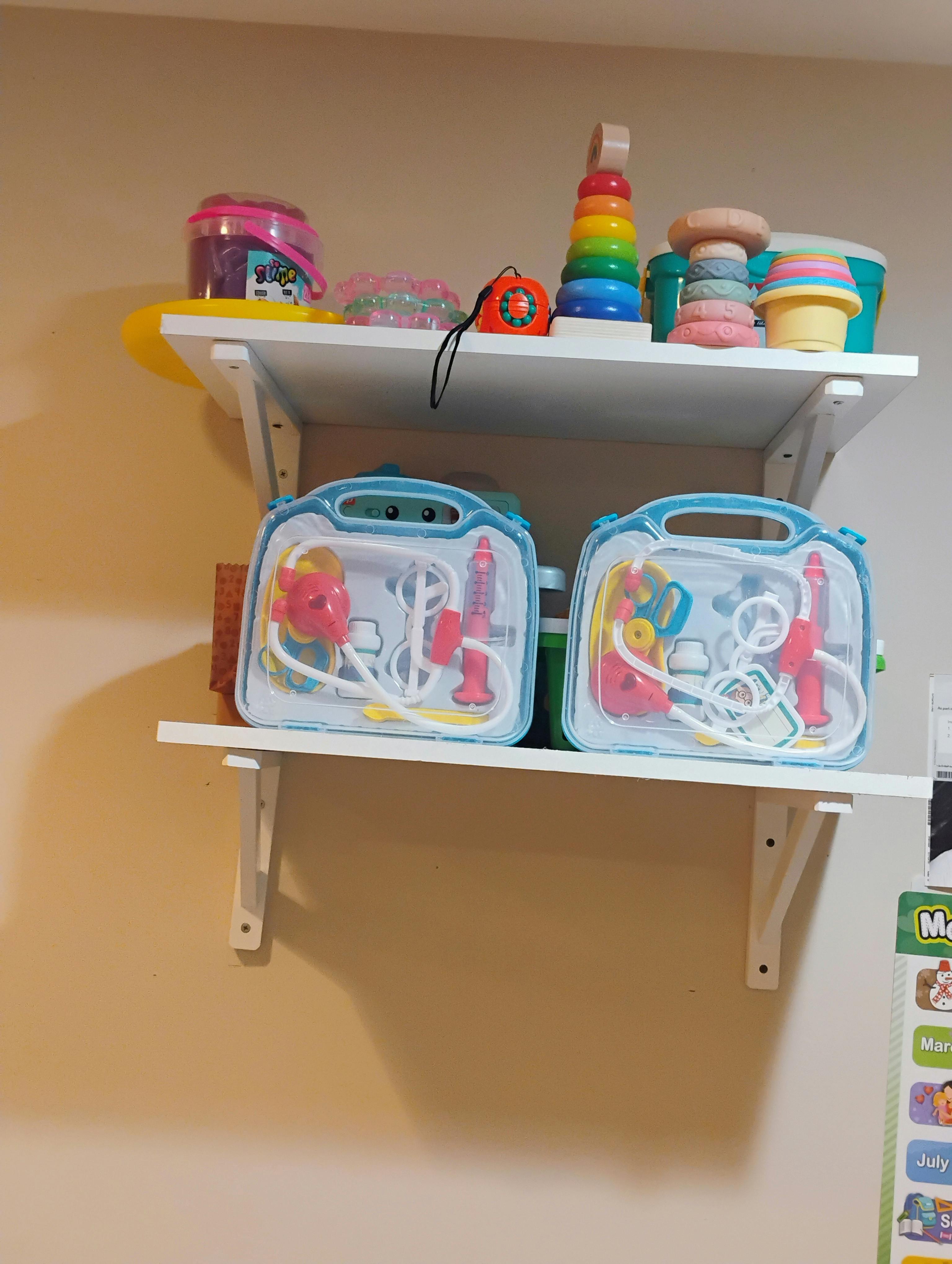 Two shelves of children's toys, including doctor play kits, stacking rings, and slime
