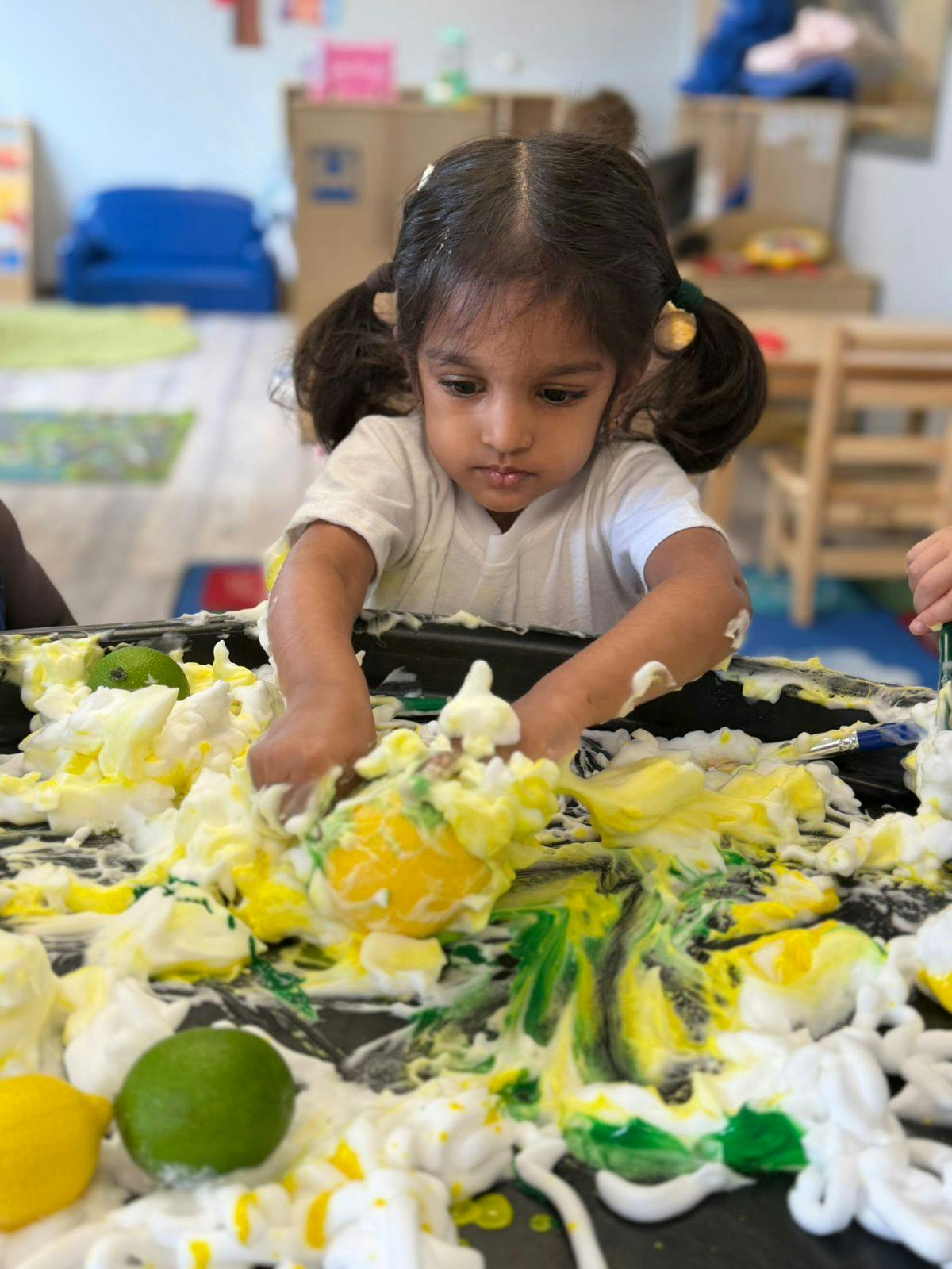 Child playing with foam and fruit in a classroom