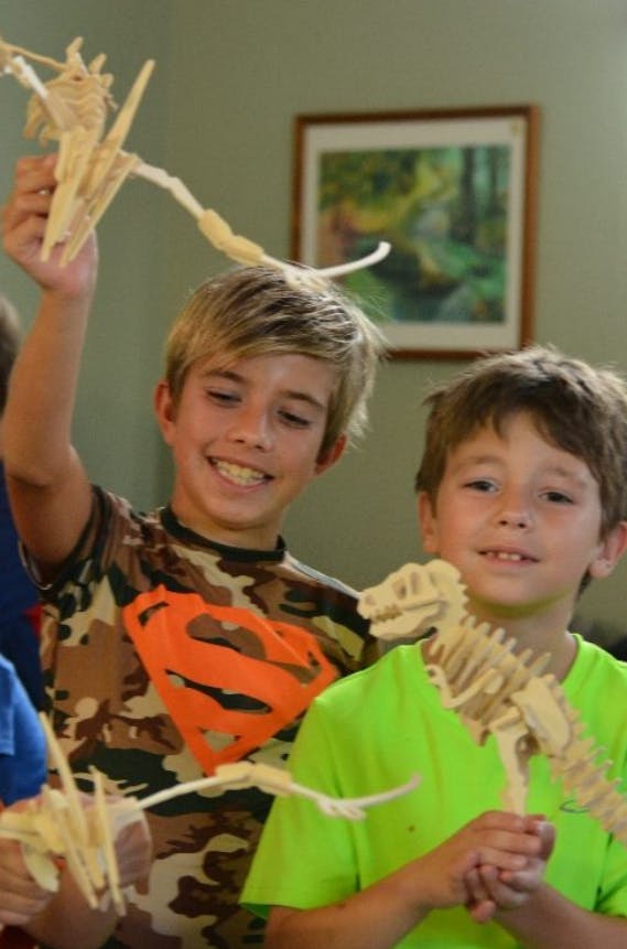 Two children holding wooden dinosaur models