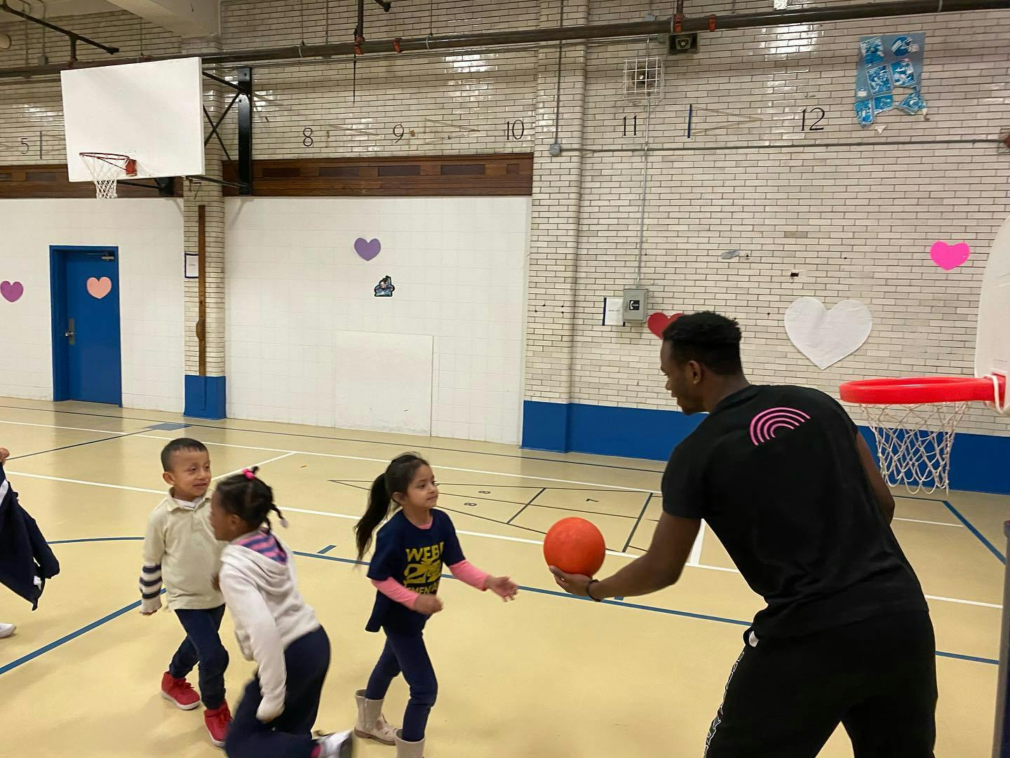 Adult and children playing with a basketball in a gym