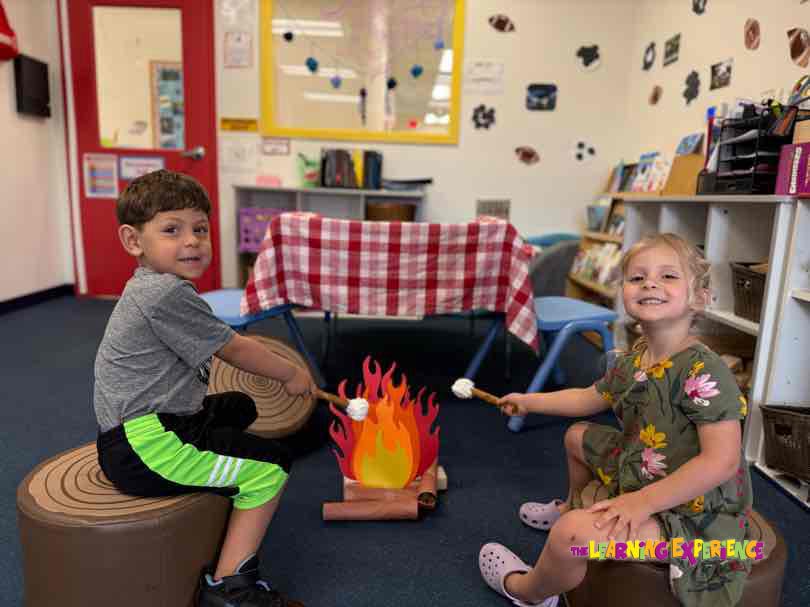 Two children roasting marshmallows over a pretend campfire