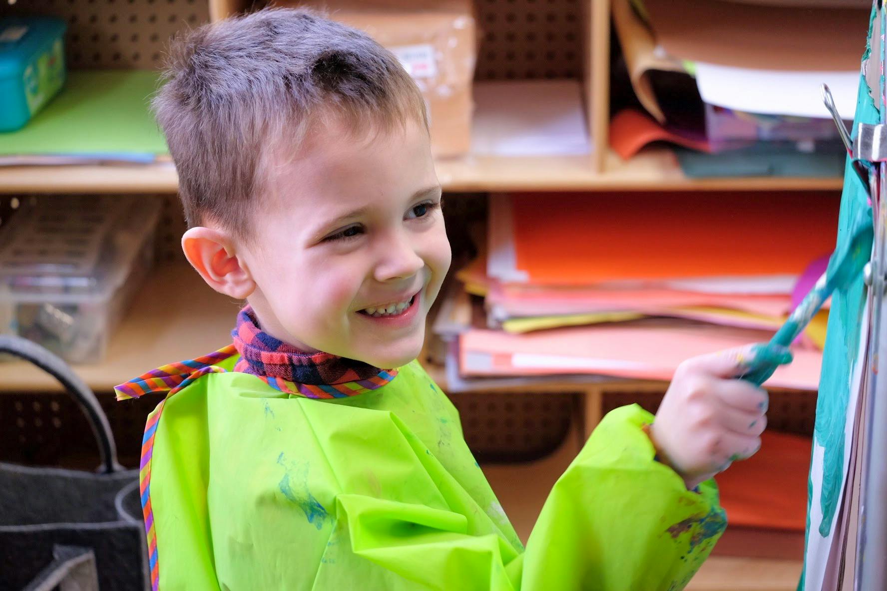 Child in a green smock painting
