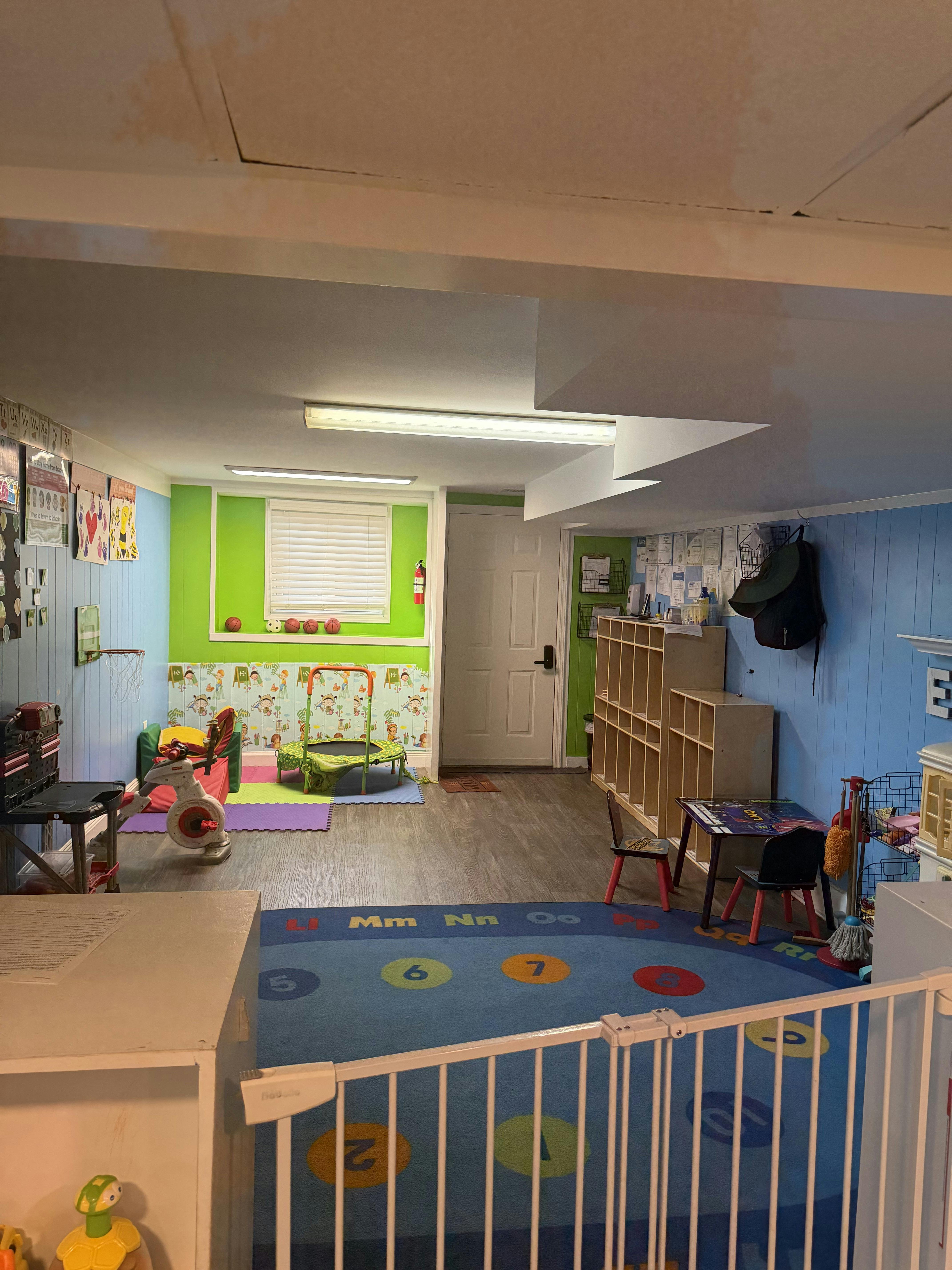 Playroom with an alphabet floor mat, small trampoline, and child-sized furniture