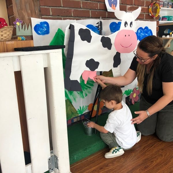 Adult and child playing with a pretend cow milking station
