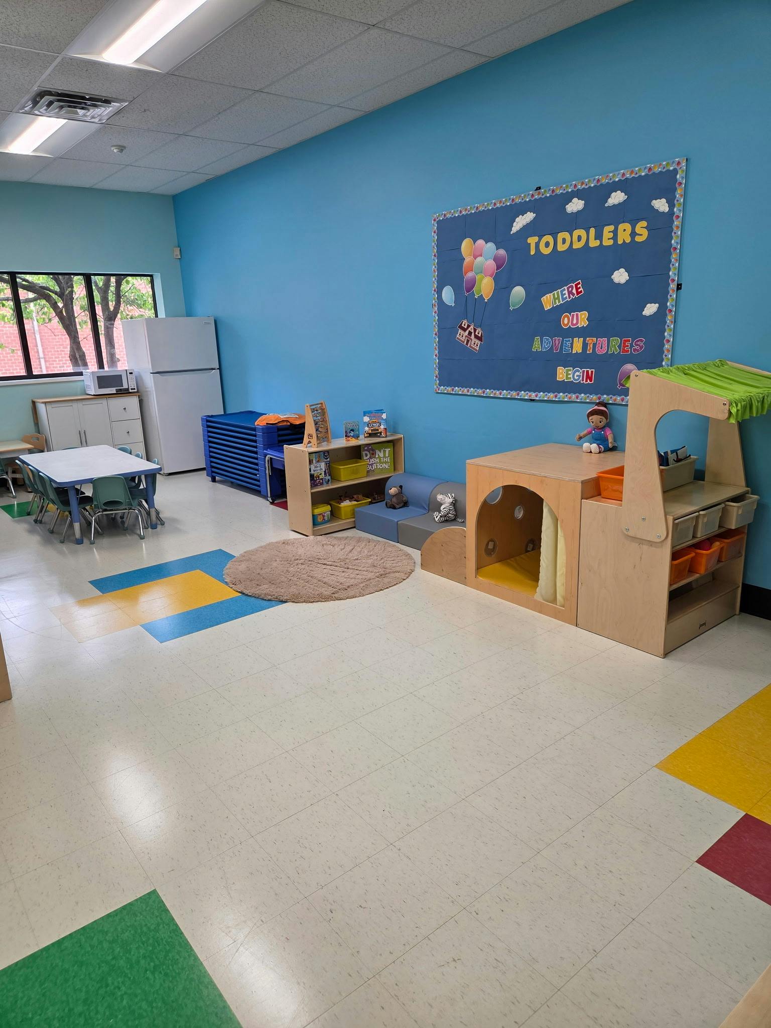 Childcare classroom with play furniture and a bulletin board titled Toddlers