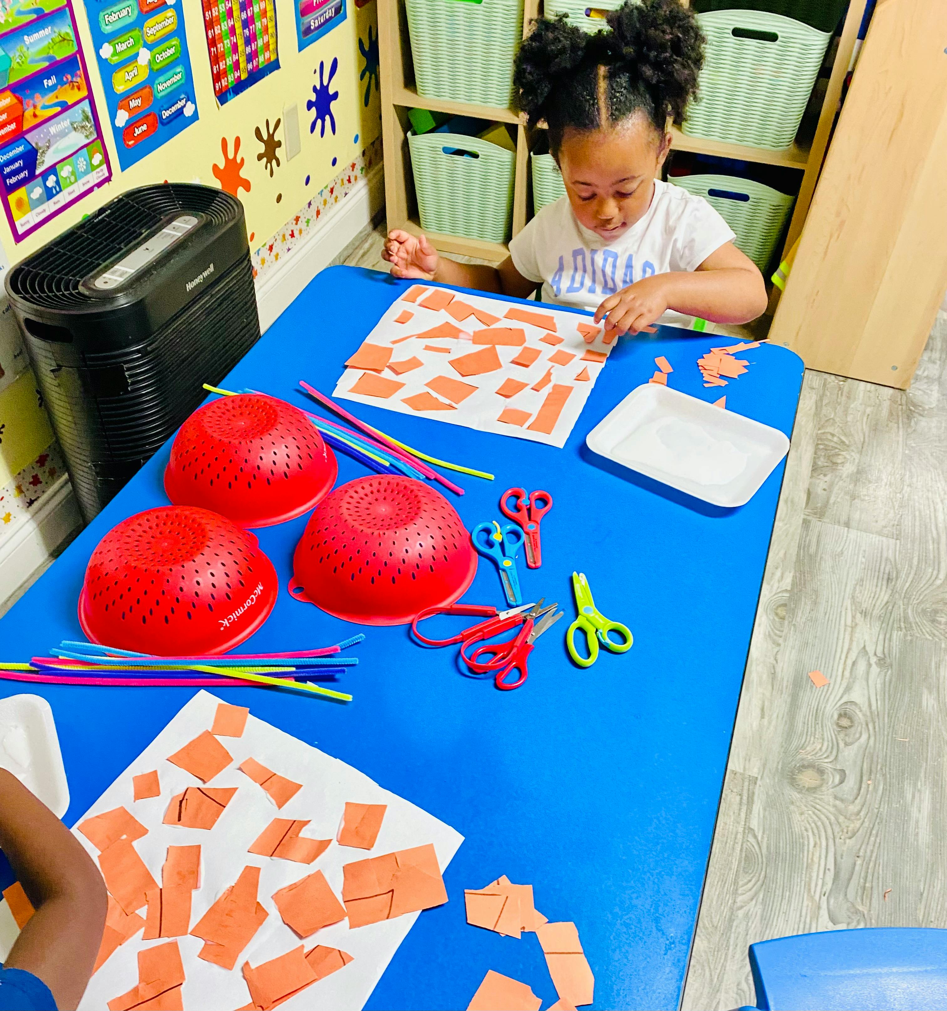 Child crafting with paper squares on a blue table