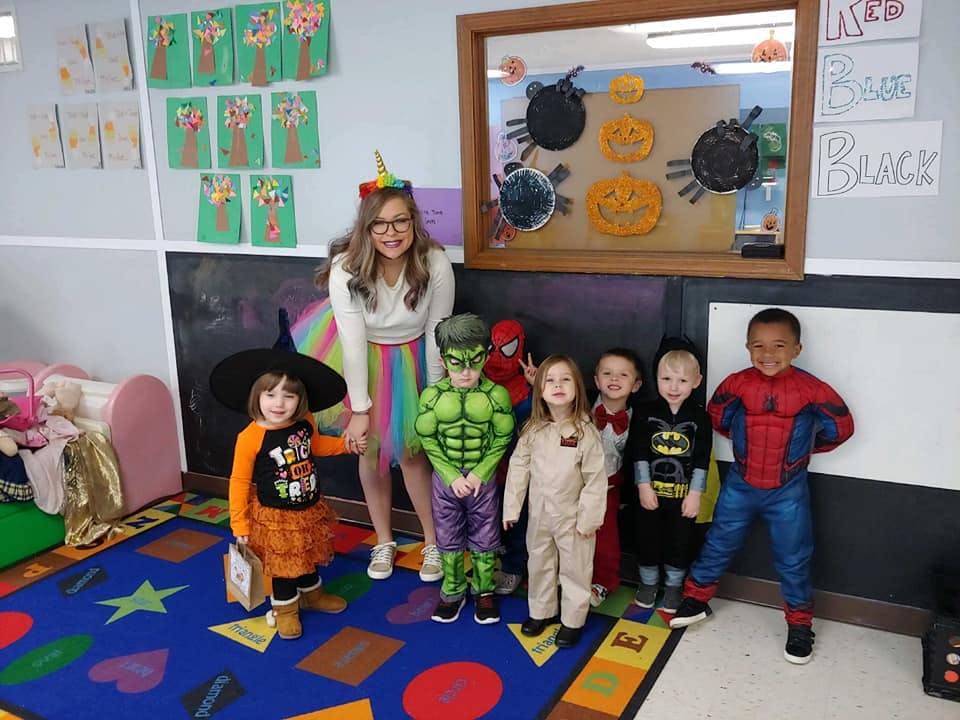 Person and multiple children in costumes in a classroom