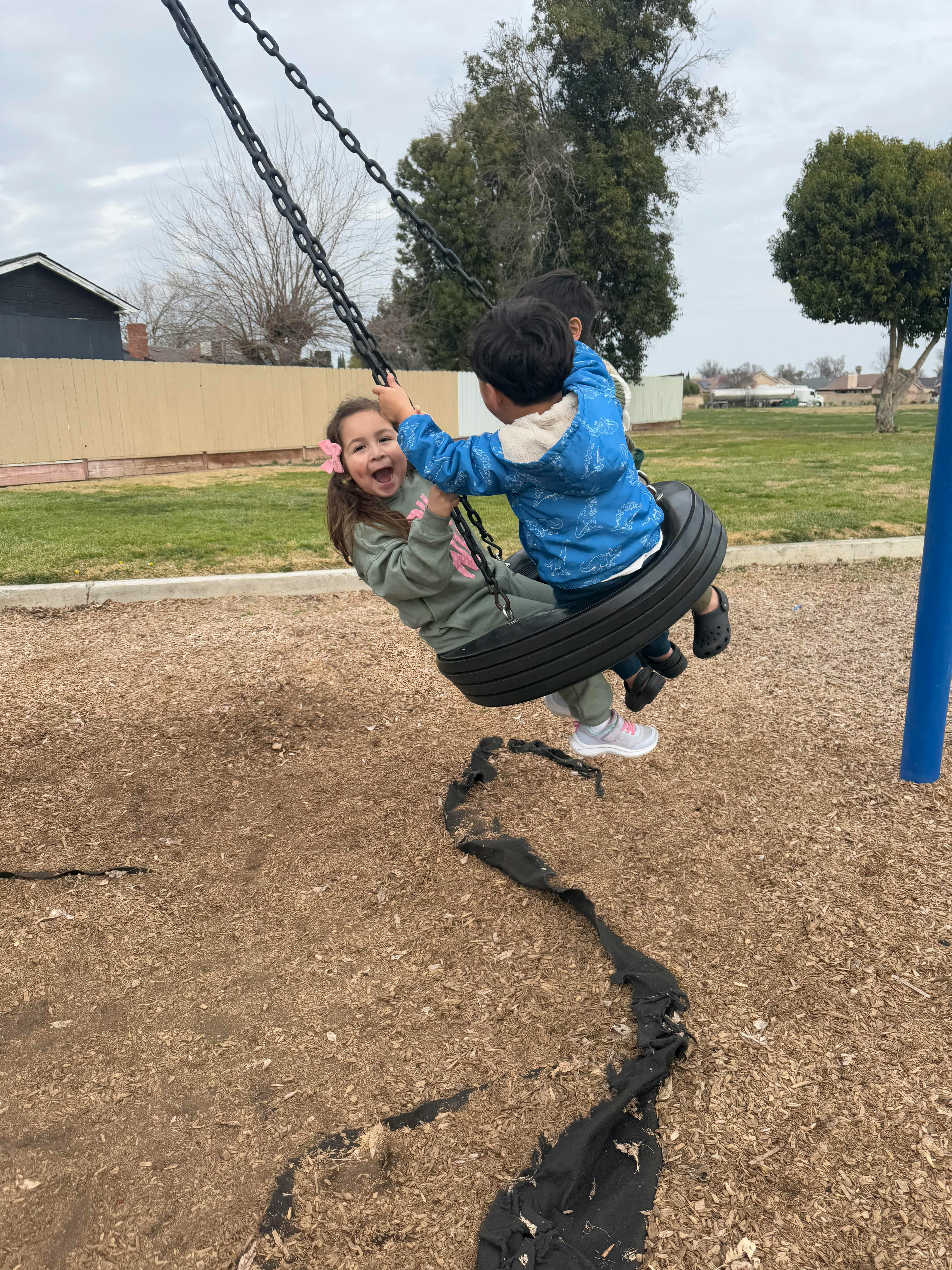 Two children on a tire swing at a playground