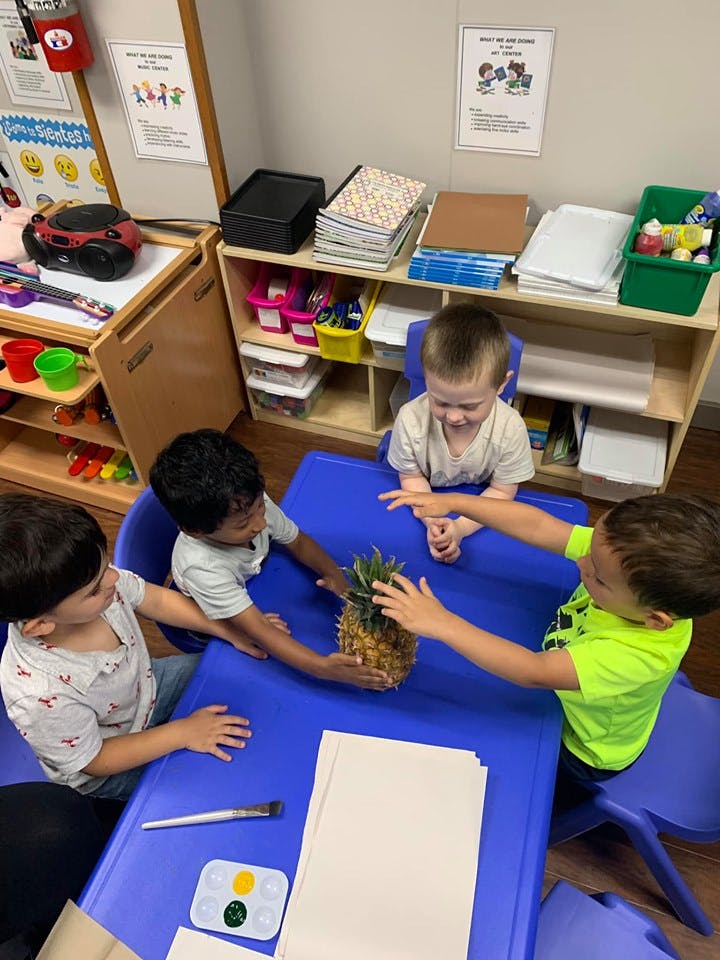 Four children at a table with a pineapple