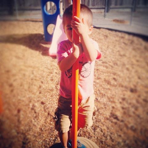 Child holding onto a pole on a playground