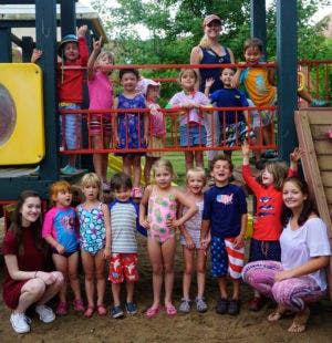 Group of children and adults posing on and around playground equipment
