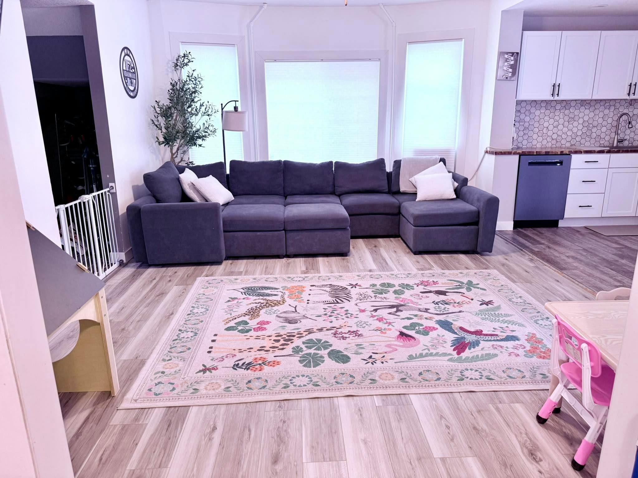 Spacious living area with a dark sectional sofa and an animal print area rug