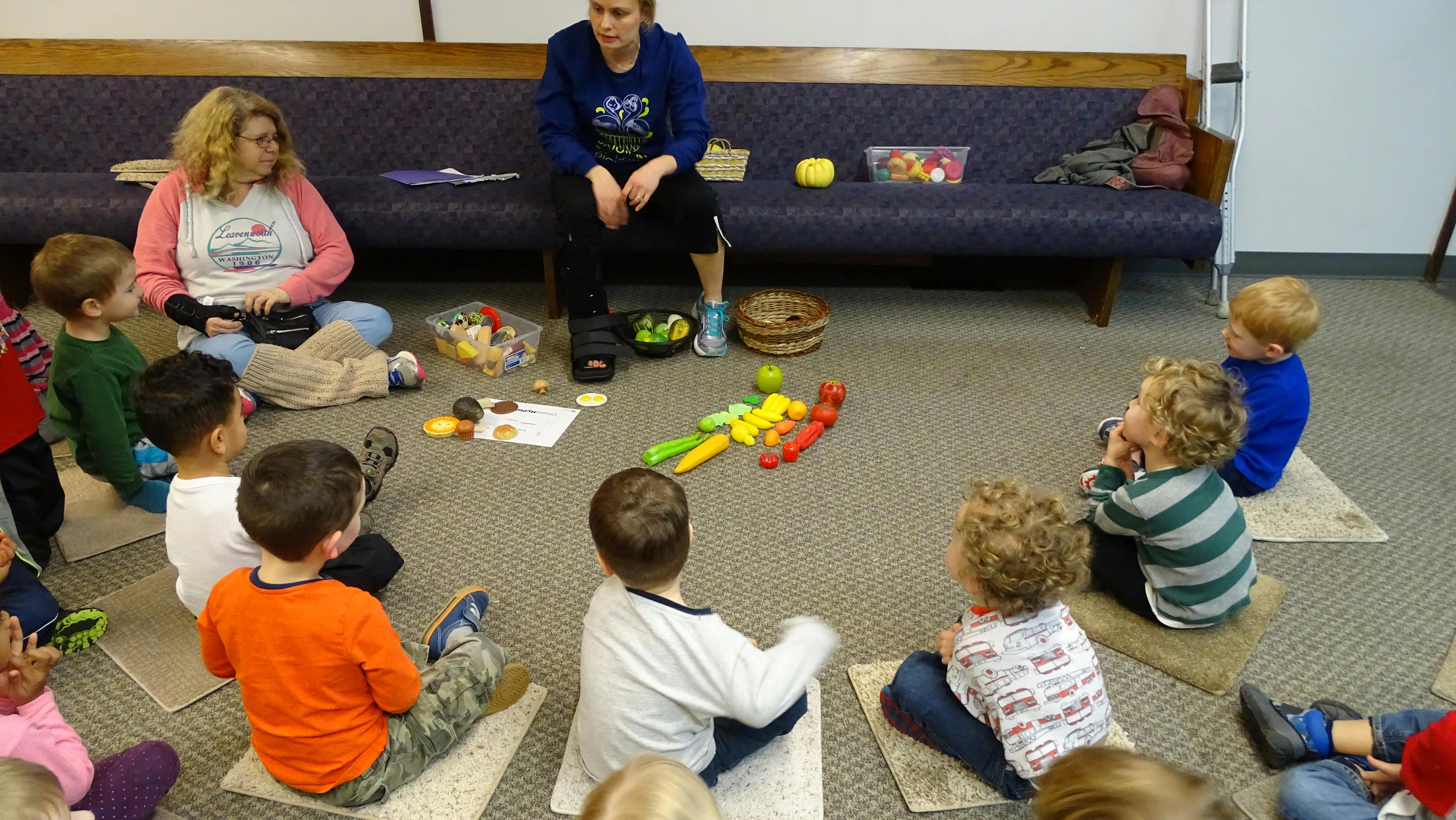 Two people and several children sitting on the floor in a circle