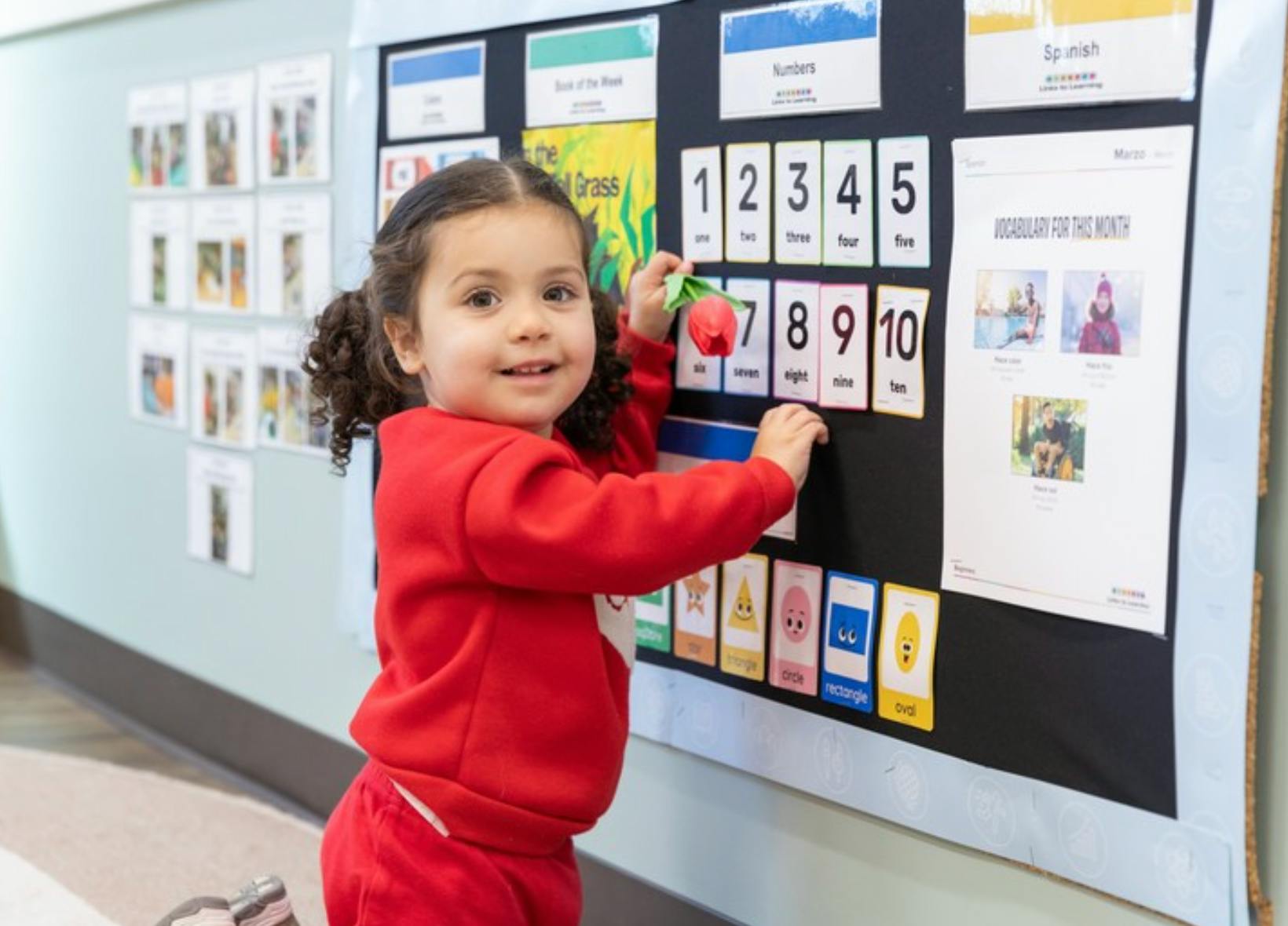 Child interacts with number and shape cards on a classroom board