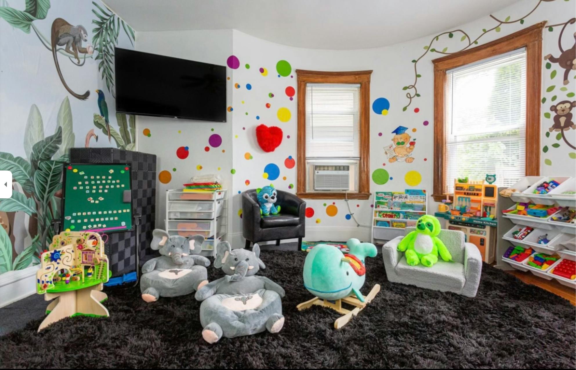 Playroom with colorful wall decals, small chairs, and stuffed animals