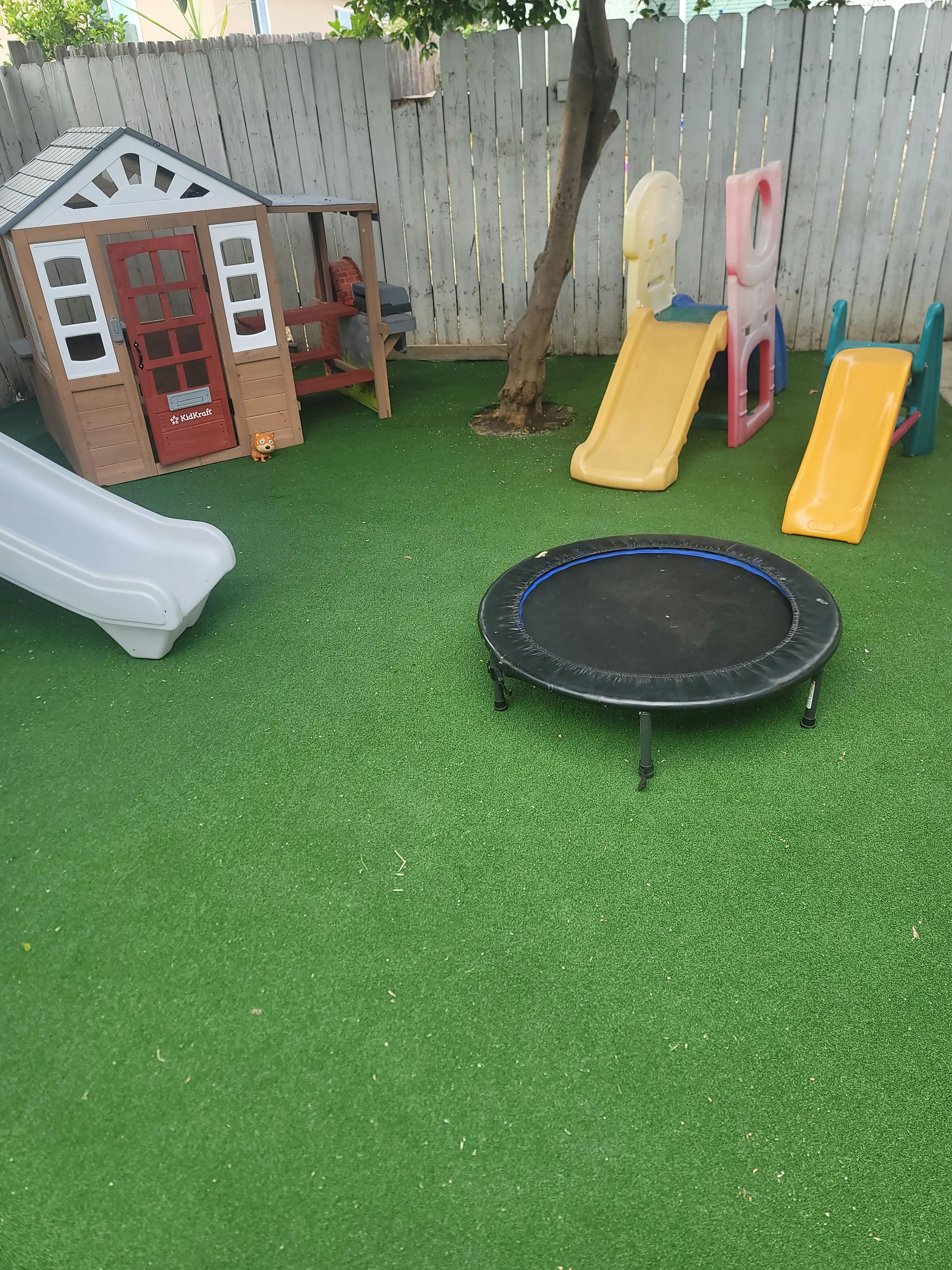 Playground with a playhouse, slides, and a trampoline