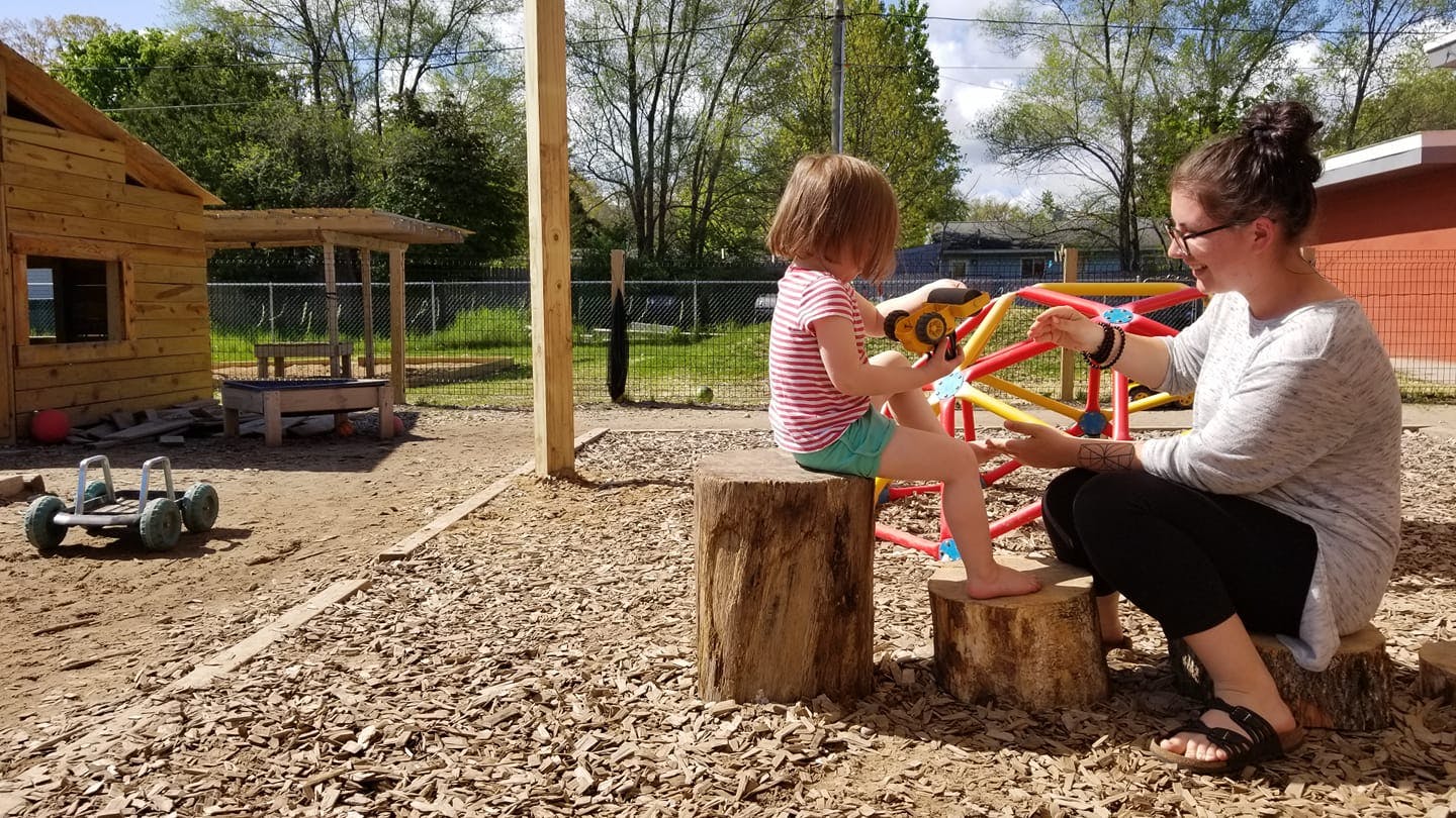 Adult and child sitting on tree stumps on a playground