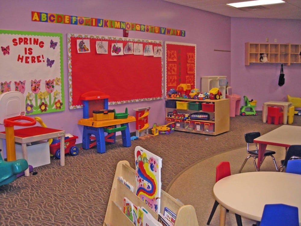 Preschool classroom with play tables, toys, and bulletin boards